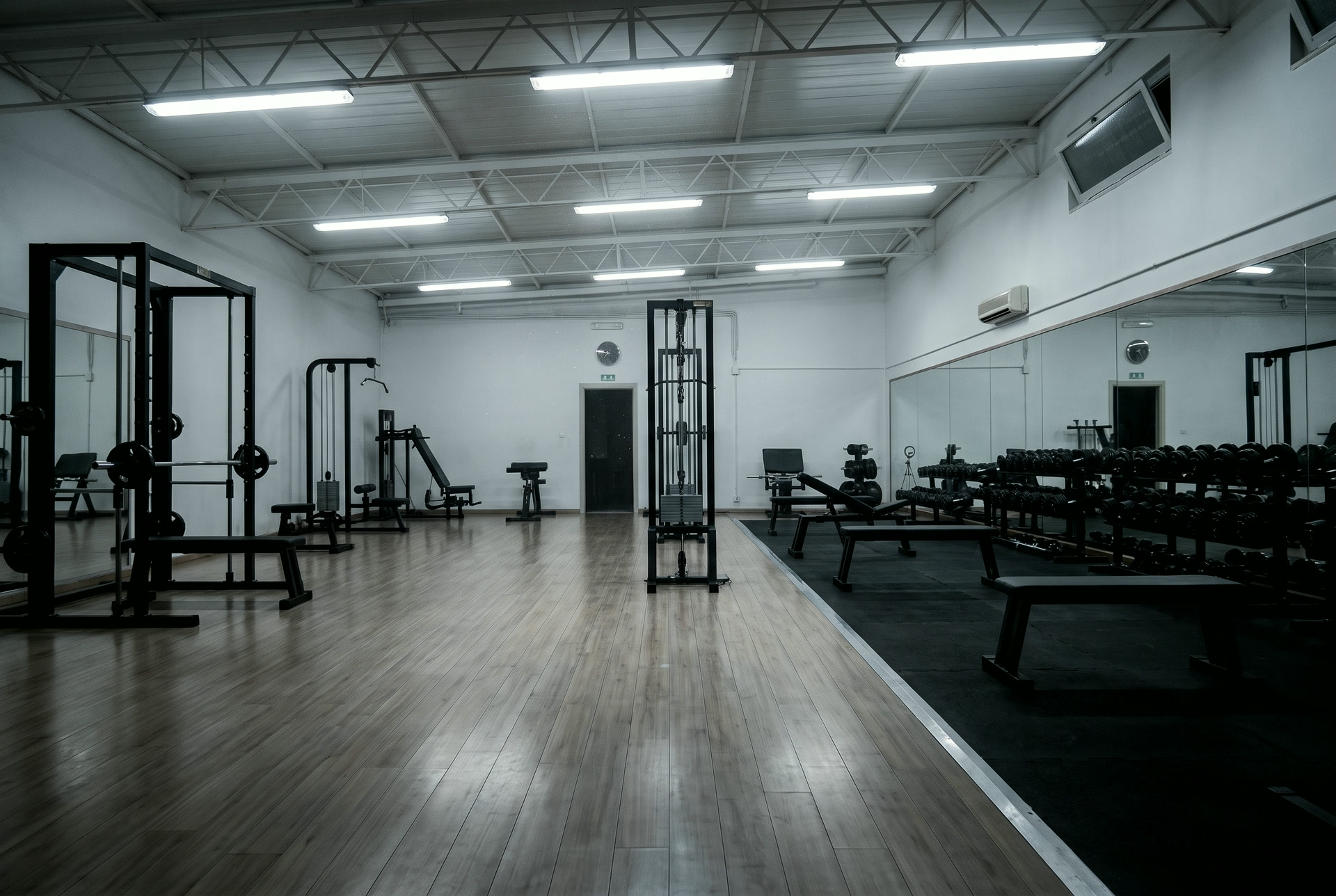 La sala pesi con il parquet, i rack neri e la parete a specchio